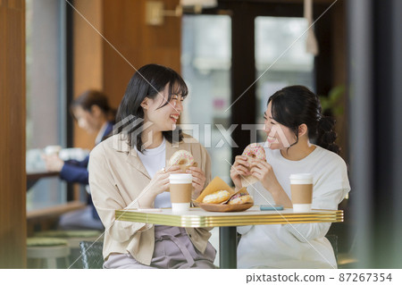 在咖啡館吃甜甜圈的年輕女人 87267354