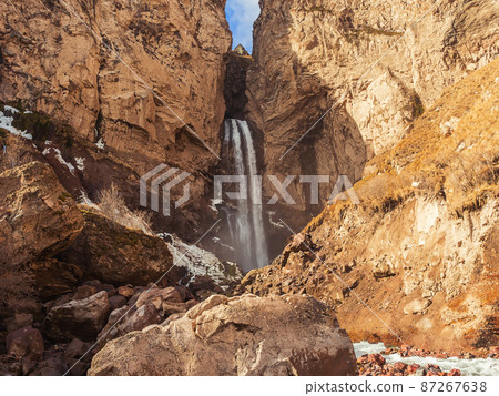 A high mountain waterfall flows down in the rocks of a suburban gorge in the North Caucasus on an autumn sunny day A high mountain waterfall flows down in the rocks of a suburban gorge in the North Caucasus on an autumn sunny day 87267638