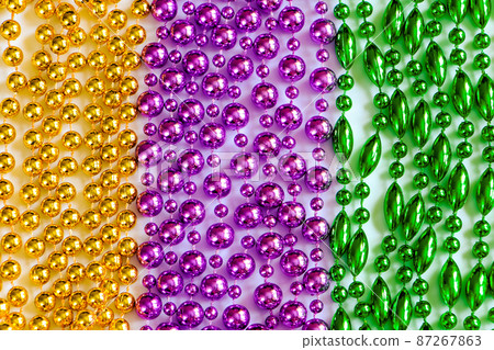 Mardi Gras background. Multi-colored beads close-up. Festive decorations in gold, green and purple colors. Fat Tuesday symbol. Mardi Gras background. Multi-colored beads close-up. Festive decorations in gold, green and purple colors. Fat Tuesday symbol. 87267863
