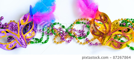 Two carnival masks with feathers and multi-colored beads on white background. Mardi Gras or Fat Tuesday symbol. Two carnival masks with feathers and multi-colored beads on white background. Mardi Gras or Fat Tuesday symbol. 87267864