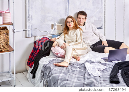 Married couple with gadgets in bed lie and watch movie on laptop. Married couple with gadgets in bed lie and watch movie on laptop. 87268494