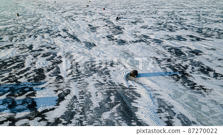 Aerial of frozen lake with ice fishing huts 87270022