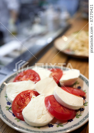 Caprese salad with tomatoes, mozzarella cheese, basil. Dark background. Close up. Top view. Caprese salad with tomatoes, mozzarella cheese, basil. Dark background. Close up. Top view. 87270421