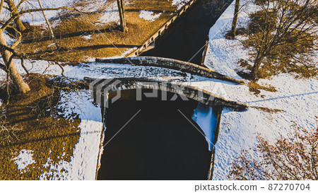 matt finish of public park bridge over small river at sawn 87270704