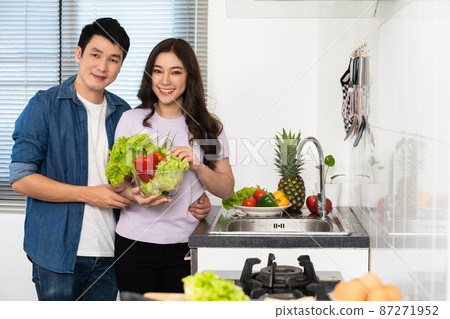 couple with preparing vegetables to cooking together in the kitchen at home. man is hugging woman 87271952