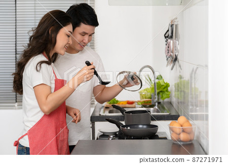 happy couple cooking and preparing food in the kitchen at home happy couple cooking and preparing food in the kitchen at home 87271971