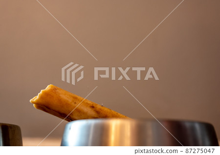 Side view of a dog chew bone with a metal bowl 87275047