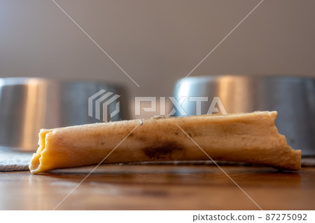 Side view of a dog chew bone with a metal bowl 87275092