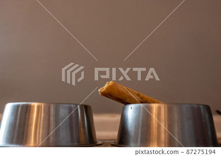 Side view of a dog chew bone with a metal bowl Side view of a dog chew bone with a metal bowl 87275194