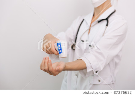 Temperature measurement gun in doctor hands. Close-up shot of doctor wearing protective surgical mask ready to use infrared isometric thermometer gun to check body temperature for virus symptoms. Temperature measurement gun in doctor hands. Close-up shot of doctor wearing protective surgical mask ready to use infrared isometric thermometer gun to check body temperature for virus symptoms. 87276652