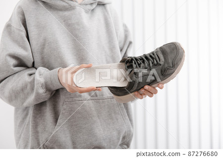 Woman putting orthopedic insole into shoe at home. Sports girl fitting orthopedic insole indoors, close up. Foot care banner. Flat Feet Correction. Treatment and prevention of foot diseases. Woman putting orthopedic insole into shoe at home. Sports girl fitting orthopedic insole indoors, close up. Foot care banner. Flat Feet Correction. Treatment and prevention of foot diseases. 87276680