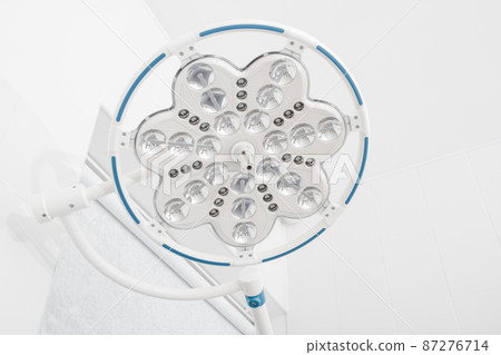 Surgical round light. Medical led ceiling lamp. Empty operating room in a hospital with treatment table lamp. Blank Emergency Surgery Room concept. Surgical equipment. Clinic interior for background. Surgical round light. Medical led ceiling lamp. Empty operating room in a hospital with treatment table lamp. Blank Emergency Surgery Room concept. Surgical equipment. Clinic interior for background. 87276714