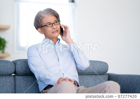 老人坐在沙發上打電話 87277420