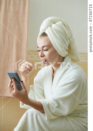 Woman Brushing Teeth and Reading News Woman Brushing Teeth and Reading News 87280718