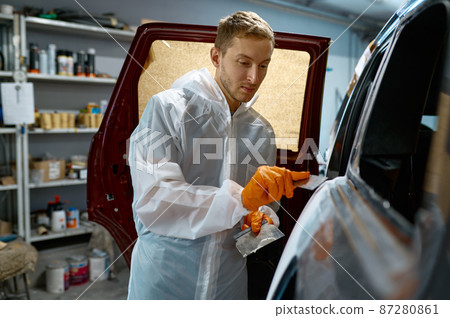 Mechanic puttying plastering car body in garage Mechanic puttying plastering car body in garage 87280861