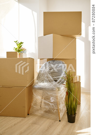 Stacked cardboard boxes and packed chair indoors Stacked cardboard boxes and packed chair indoors 87280884