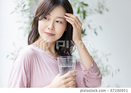 A woman in a loungewear with a glass of water A woman in a loungewear with a glass of water 87280951