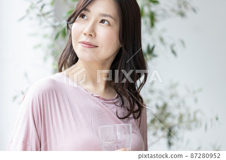 一個穿著家居服的女人,端著一杯水 一個穿著家居服的女人,端著一杯水 87280952