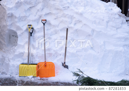 Big pile of snow. Nearby are shovels for snow removal. Bright orange spades. Background, texture 87281833