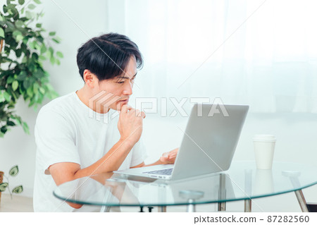 A man who thinks while using a computer A man who thinks while using a computer 87282560