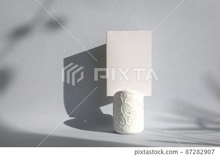 Blank white card on top of a white holder with shadow on wall. 87282907