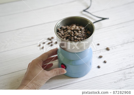 Coffee beans inside an electrical grinder. 87282908