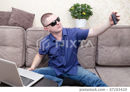 A man in a blue shirt blogs and takes a selfie on his phone. A man in a blue shirt blogs and takes a selfie on his phone. 87283420