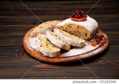 Traditional Christmas stollen cake with marzipan and dried fruit isolated on wooden background Traditional Christmas stollen cake with marzipan and dried fruit isolated on wooden background 87283566