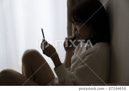 Woman sitting in a dark room Woman sitting in a dark room 87284650