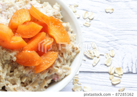 Oatmeal porridge with fresh apricots on a wooden background. 87285162