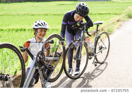 female rider is pumping her bike tire on a sideroad female rider is pumping her bike tire on a sideroad 87285705