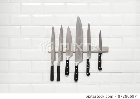 Six Japanese knifes hanging on white wall tile Six Japanese knifes hanging on white wall tile 87286697