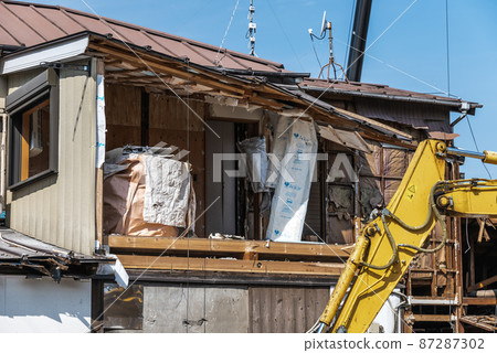 Demolition of a wooden house: Heavy machinery demolishing the interior Demolition of a wooden house: Heavy machinery demolishing the interior 87287302