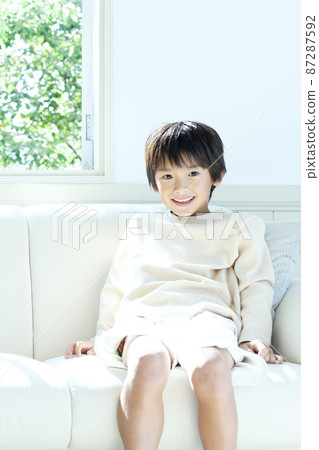 A smiling boy sitting on the sofa A smiling boy sitting on the sofa 87287592