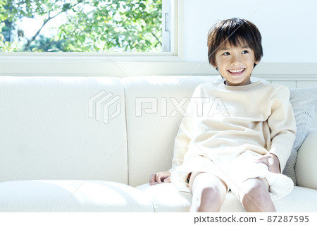 A smiling boy sitting on the sofa A smiling boy sitting on the sofa 87287595