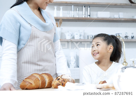 Mother and daughter carrying bread Mother and daughter carrying bread 87287691