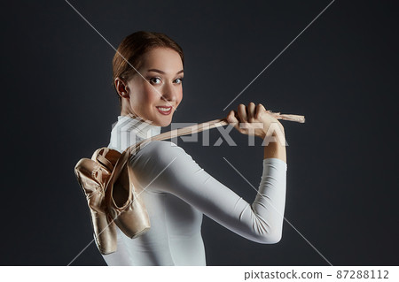 portrait of a ballerina holding pointe shoes. photo shoot in the studio on a dark background portrait of a ballerina holding pointe shoes. photo shoot in the studio on a dark background 87288112