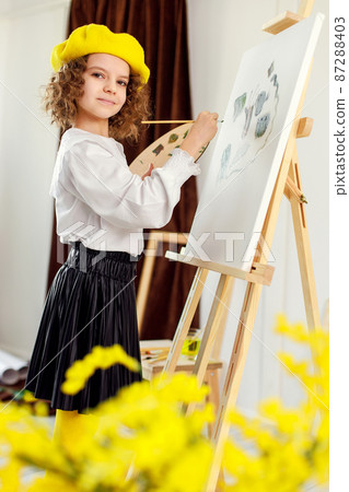 Little girl painting a picture in a studio or art school. Creative pensive painter child paints a colorful picture on canvas in workshop. Talented kids Little girl painting a picture in a studio or art school. Creative pensive painter child paints a colorful picture on canvas in workshop. Talented kids 87288403