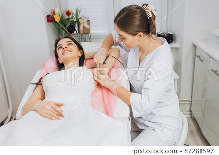 Procedure removal of hair permanently in a woman's armpits using metod electro epilation. Permanent removal of unwanted hair. The needle of electrolysis. Doctor in cosmetic medical cabinet. Procedure removal of hair permanently in a woman's armpits using metod electro epilation. Permanent removal of unwanted hair. The needle of electrolysis. Doctor in cosmetic medical cabinet. 87288597