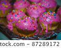 Freshly baked vanilla muffins are garnished with sweet icing and topping. 87289172