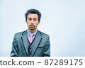 Shocked businessman with tousled hair looks into the camera. 87289175