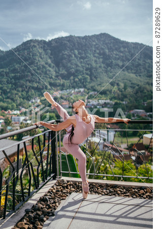 Young fit ballerina in pointes against mountainous landscape Ballerina dancing Young fit ballerina in pointes against mountainous landscape Ballerina dancing 87289629