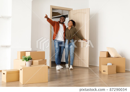 Excited Black Spouses Entering Their New Home, Husband Pointing Aside Excited Black Spouses Entering Their New Home, Husband Pointing Aside 87290034