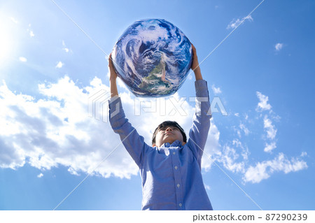 A boy playing with a ball with an earth pattern under the blue sky 87290239