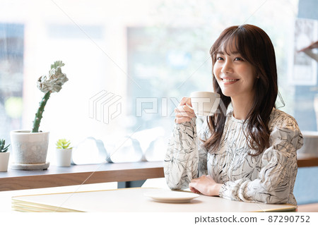 Young woman drinking coffee at the window seat of a cafe 87290752