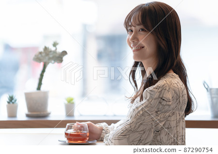 一位年輕女子在咖啡館靠窗的座位上喝茶 一位年輕女子在咖啡館靠窗的座位上喝茶 87290754