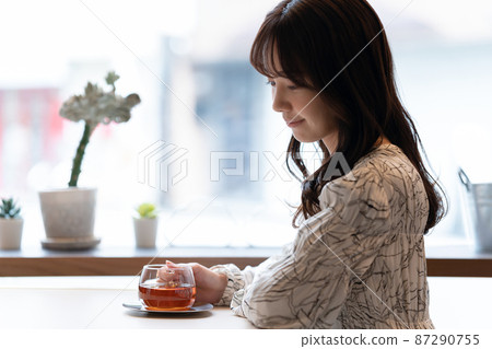 一位年輕女子在咖啡館靠窗的座位上喝茶 一位年輕女子在咖啡館靠窗的座位上喝茶 87290755