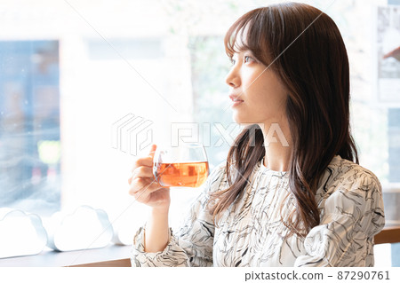 A young woman drinking tea at a cafe window seat A young woman drinking tea at a cafe window seat 87290761