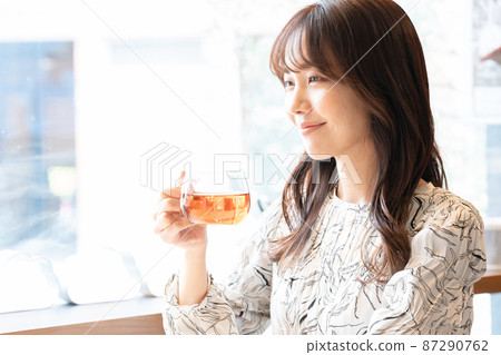 A young woman drinking tea at a cafe window seat A young woman drinking tea at a cafe window seat 87290762