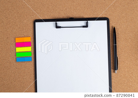 A notepad with a blank sheet of paper and a pen next to it on the table. A notepad with a blank sheet of paper and a pen next to it on the table. 87290841